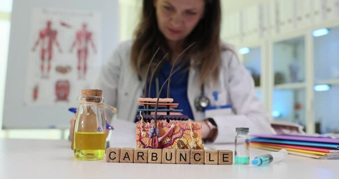Female doctor writes on document at desk with medical supplies including blocks showing Carbuncle. Studying information about type of skin infection