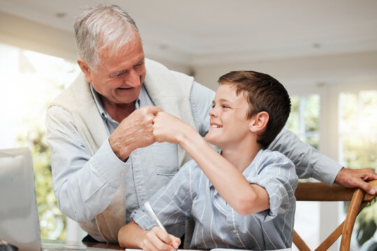 Old man, child and happy with fist bump in home for homework success, learning development and studying. Grandfather, boy kid and celebration at dining table for exam knowledge and assignment support