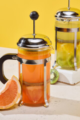 Vibrant Fruit-Infused Teas in Modern French Press with Bold Yellow Background