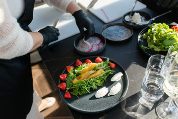 Fresh sweet Pears salad with microgreens, strawberries, pitahaya, and white soft cheese on a black plate	