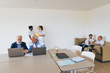 Doctors working on laptops in hospital meeting room with nurses