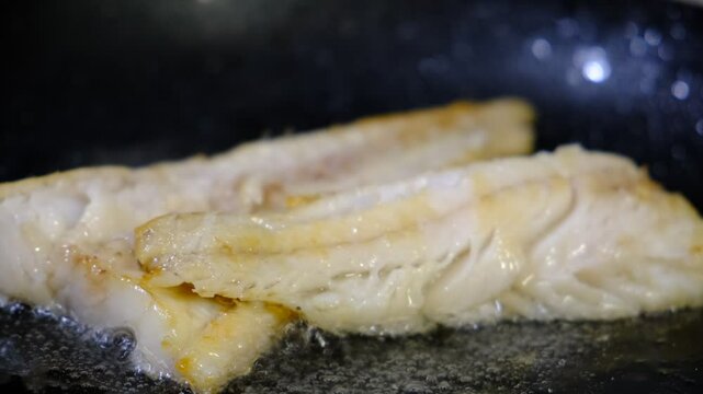 Cooking Indoors pan grilled seasoned Cod fillets on Stovetop, iron cast pan, close up boiled oil, deep fried. White meat