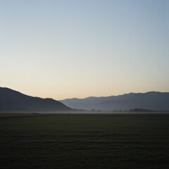 Obraz premium A tranquil landscape of mountains over a green agricultural field