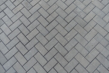 Texture of grey concrete pavement with single herringbone layout