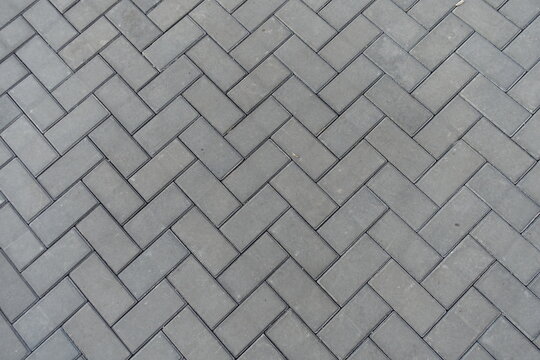 Texture of grey concrete pavement with single herringbone layout