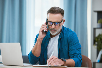 Man, phone call and home office writing in notebook, mature and business person or taking notes...