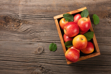 Ripe red apples in wooden box on a wooden table