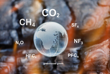 The impact of greenhouse gases on global warming and climate change concept. Glass globe planet on...