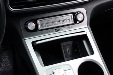 Electric Car climate control. Turning on the air conditioning of a car on the climate control panel. Car interior with climate-control view. Glove box in the center console of the car.