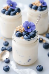 Delicious yogurt parfaits topped with fresh blueberries and flowers, perfect for summer breakfasts or desserts