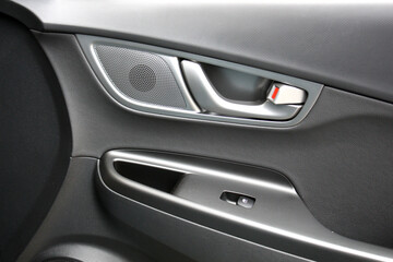 Door handle with music speaker of a modern electric car. Black interior of the luxury modern car. Passenger door trim.