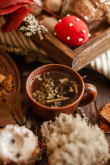 An idyllic autumn Thanksgiving scene on a wooden table with tea in a clay mug, leaves, twigs, pine cones. Hand-made decor and warm colors create a  comfortable atmosphere.