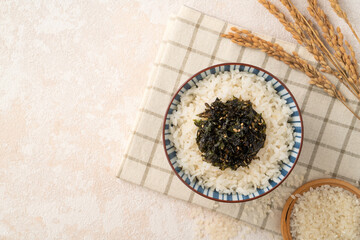 A bowl of white rice topped with seasoned seaweed and white sesame.
