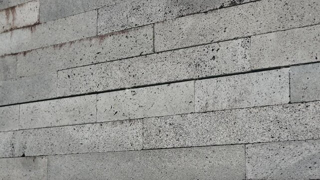 Detailed image of a concrete brick wall showcasing the texture, pattern, and grey tones of the bricks. Close-Up of Concrete Brick Wall Showing Texture and Pattern