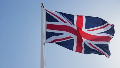 The Union Jack flutters prominently against a bright blue sky, embodying British history and pride with its distinctive red, white, and blue design.