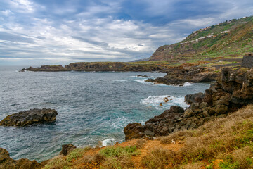 View of El Sauzal coastline in Tenerife with rocky shores, ocean waves, and lush hillsides