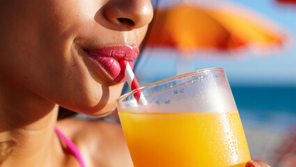 A woman sips a cold beverage through a straw, savoring the moment while lounging at a beachside location