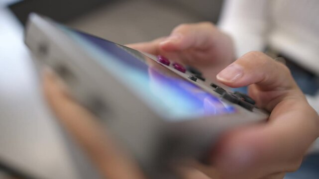 Top view of beautiful young woman sitting on sofa at home enjoying video game on portable retro console