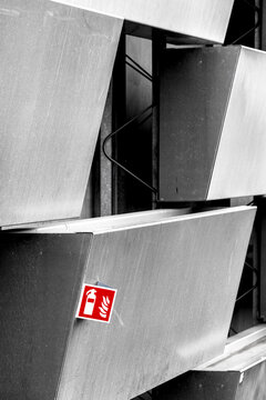 Close-up of fire emergency sign on a modern metallic building facade with geometric shapes, showing attention to safety protocols and structured urban design.