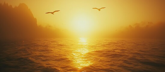 A golden sunrise shines over the vast ocean with soaring birds
