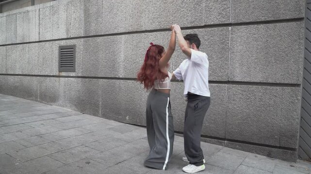 Energetic couple performing latin dance routine on urban street