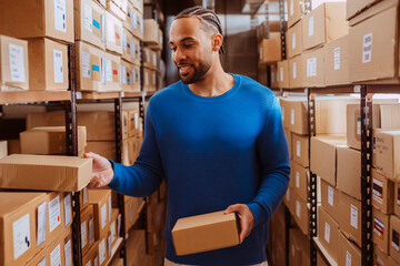 Young storekeeper managing packages in warehouse, preparing goods for delivery.
