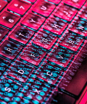 Close-up of a laptop keyboard with digital code overlay representing cybersecurity and cyber crime concepts
