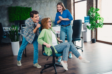 Fototapeta premium Diverse group of colleagues enjoying a fun team-building activity with office chairs, showcasing teamwork, collaboration
