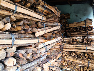 pile of stacked firewood stored in a shed. bundle of stack firewood for home personal use and displayed for sale.
