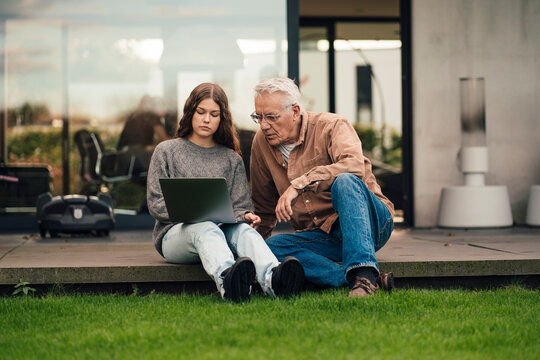 Grandfather and granddaughter discussing sustainable energy plans in the garden