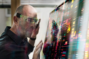 Man using augmented reality glasses to interact with a digital screen in a modern workspace