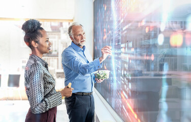 Two professionals collaborating on a digital screen with augmented reality in an office setting