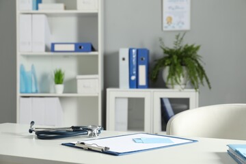 Doctor's workplace. Stethoscope, clipboard and other stationery on white table in medical office
