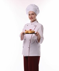 Happy confectioner in uniform holding delicious profiteroles with strawberries on white background