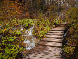 Obraz premium Wooden walkpath in Plitvice National Park. Splendid autumn in forest with pure water lake. Picturesque landscape of Croatia, Europe. Beauty of nature concept background.