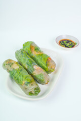 Fresh and healthy vietnamese spring rolls with soy sauce dipping, served on long white plate, on isolated white background