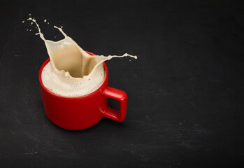 Red Coffee glass cup with splashes on a black background. Copy space.