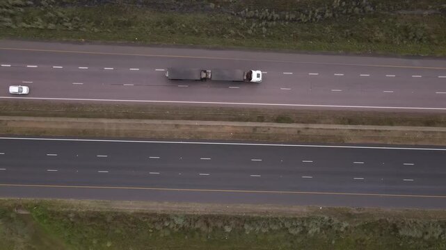 Drone clip of a dual carriageway highway with cars on both sides and a truck transporting goods