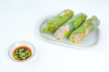 Fresh and healthy vietnamese spring rolls with soy sauce dipping, served on long white plate, on isolated white background