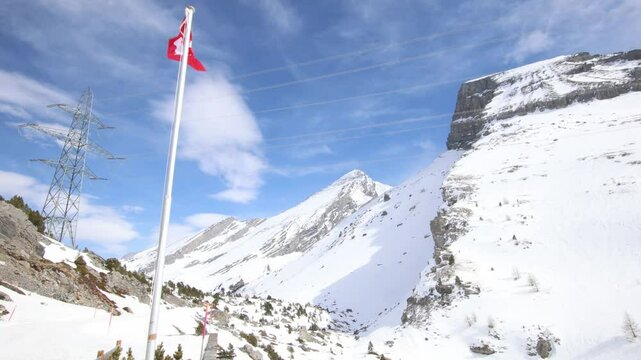 Swiss flag moving in extreme wind, windy winter mountain landscape