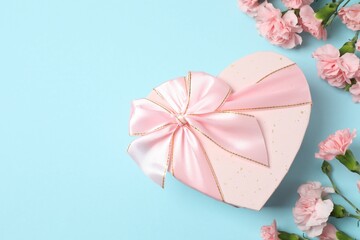 Happy Mother's Day. Beautiful bouquet of pink carnations with gift box on a colored background