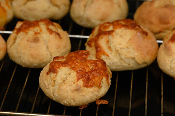 Freshly baked cheese rolls emerge from the oven, golden and warm, ready to delight taste buds in a cozy kitchen setting
