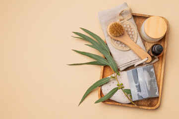 Natural skincare products and tools on wooden tray.