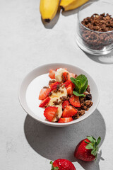 Natural Greek yogurt with homemade chocolate granola, strawberries and banana in a bowl