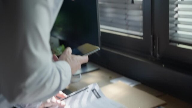 Spy or secret agent reviews classified documents spread across office desk, discreetly snapping photos with smartphone. espionage, covert operations, and intelligence gathering, surveillance. thief