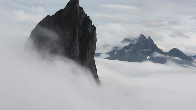 View from Mount Hesten in Norway on Iconic Mountain Segla in light of epic sunsetcovered in fog