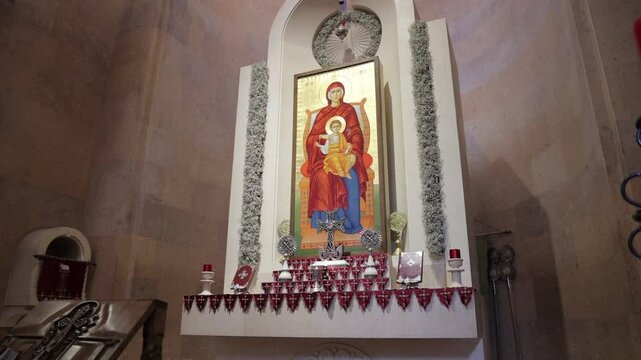 painting of Virgin Mariam, candle and crosses against a stone wall of historic architecture