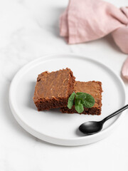 Pieces of chocolate brownies on a light background. Delicious and sweet homemade pastries for breakfast. Vegetarian dessert.
