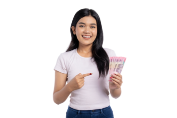 Happy young Asian woman smiling and proudly pointing at a fan of Indonesian rupiah banknotes, isolated on transparent background
