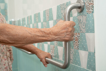 Asian elderly woman patient use handrail safety in toilet support rail in bathroom.
